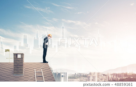 Engineer man standing on roof and looking down. Mixed media Engineer man standing on roof and looking down. Mixed media 48859161