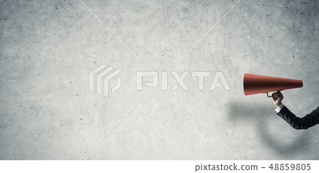 Hand of businesswoman holding red paper trumpet against concrete background 48859805