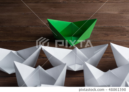 Business leadership concept with white and color paper boats on wooden table Business leadership concept with white and color paper boats on wooden table 48861398