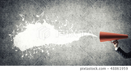 Hand of businesswoman holding red paper trumpet against concrete background Hand of businesswoman holding red paper trumpet against concrete background 48861959