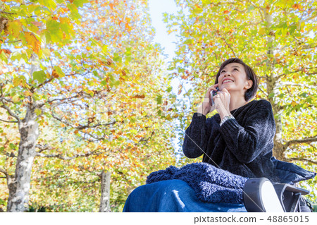 女人最新的電動輪椅走沿著大道的鳳梨 48865015
