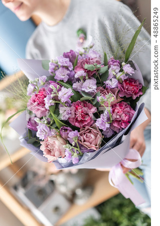beautiful fresh cut bouquet of mixed flowers in woman hand. the work of the florist at a flower shop beautiful fresh cut bouquet of mixed flowers in woman hand. the work of the florist at a flower shop 48865249