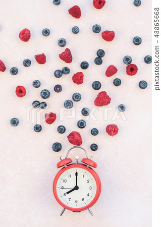 Composition with berries and red alarm clock Composition with berries and red alarm clock 48865668