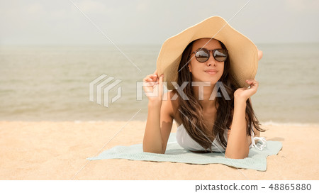 Young happy Asian woman with sunhat lying at the Young happy Asian woman with sunhat lying at the 48865880