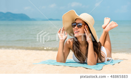 Young happy Asian woman with sunhat lying at the Young happy Asian woman with sunhat lying at the 48865883