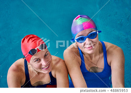 Two smiling swimmer women relaxing in the pool Two smiling swimmer women relaxing in the pool 48865953
