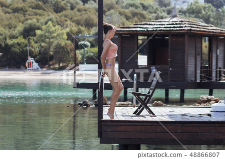 Woman in swimsuit leaning on railing 48866807