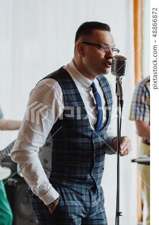 Retro fifties singer with vintage microphone and sunglasses. Studio shot Retro fifties singer with vintage microphone and sunglasses. Studio shot 48866872