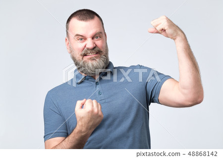 Handsome middle age european bearded man over showing arm muscle 48868142
