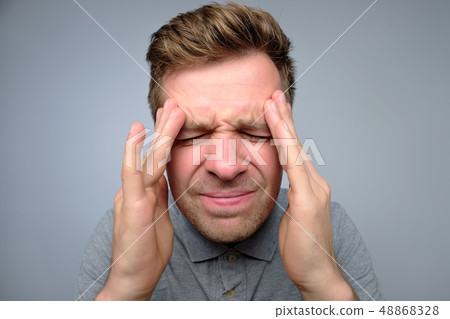 Upset unhappy young man squeezing head with hands, suffering from headache. Upset unhappy young man squeezing head with hands, suffering from headache. 48868328