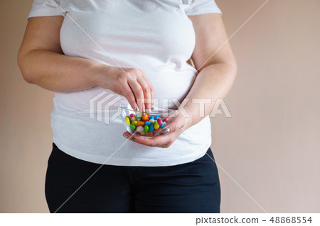 overweight woman eating unhealthy sweet candies 48868554
