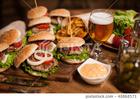 Close up of fresh burgers with a glass of beer on vintage wooden table Close up of fresh burgers with a glass of beer on vintage wooden table 48868571