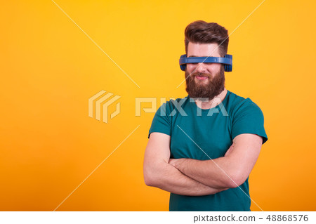 Attractive bearded man fooling around with headset over yellow background 48868576