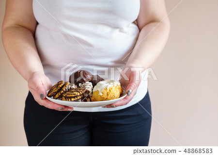 obese woman eating sweets holding plate of cookies obese woman eating sweets holding plate of cookies 48868583