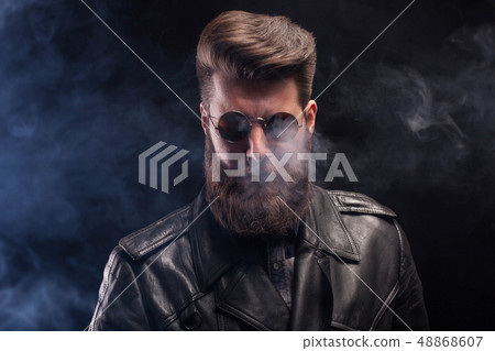 Rich handsome bearded man with sunglasses and leather jacket over black background 48868607