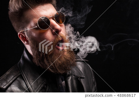 Portrait of nice man playing with cigarette smoke over black background 48868617