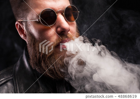 Bearded man in leather jacket and brown sunglasses over black background 48868619