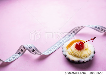 diet concept. sweet cupcake and measure tape diet concept. sweet cupcake and measure tape 48868655
