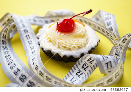 diet concept. sweet cupcake and measure tape diet concept. sweet cupcake and measure tape 48868657