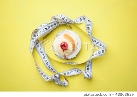 diet concept. sweet cupcake and measure tape diet concept. sweet cupcake and measure tape 48868659
