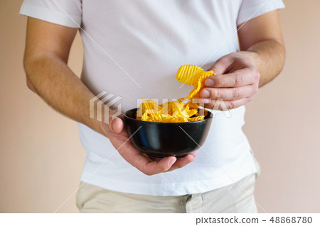 overweight man eating fattening potato chips 48868780