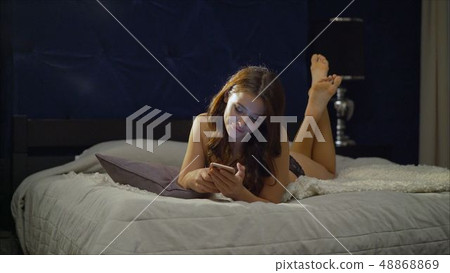 The girl in black underwear.. Young happy smile woman send message. The girl is lying on the bed The girl in black underwear.. Young happy smile woman send message. The girl is lying on the bed 48868869