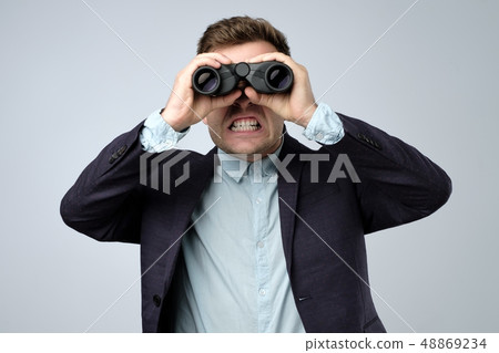 European man in suit looking wtih horror through binoculars. European man in suit looking wtih horror through binoculars. 48869234