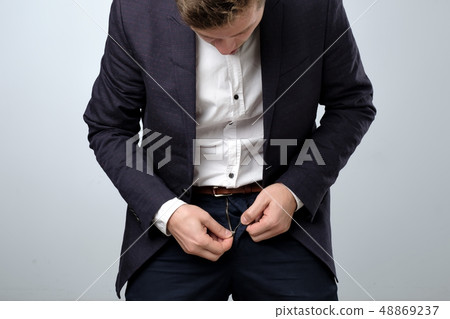 Man in suit zip his pants up. Problem with broken fly. 48869237