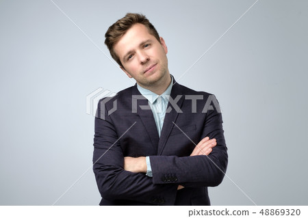 Young european businessman crossing hands looking serious at camera Young european businessman crossing hands looking serious at camera 48869320