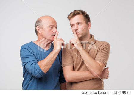Two men with suspicious look make silence gesture, touch lips with index fingers 48869934