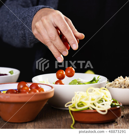 young man preparing a buddha bowl salad young man preparing a buddha bowl salad 48873291