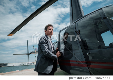 Businessman entering his private helicopter Businessman entering his private helicopter 48875455