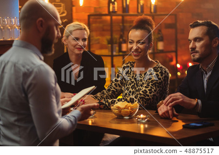 Group of friends having fun talk behind bar counter in a cafe Group of friends having fun talk behind bar counter in a cafe 48875517