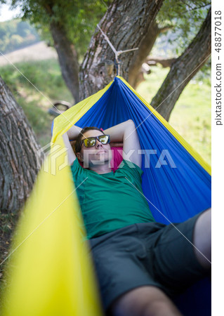 Photo of man in sunglasses lying in hammock in forest Photo of man in sunglasses lying in hammock in forest 48877018