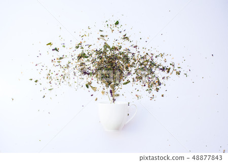 Cup and dry leaves herbal tea scattered on white Cup and dry leaves herbal tea scattered on white 48877843