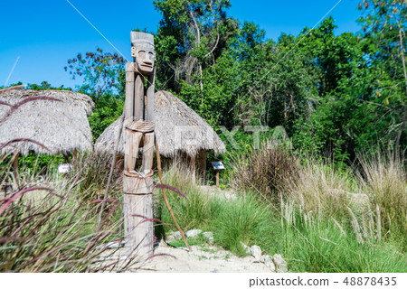 Wooden Taino idol and huts in village in Dominican Republic Wooden Taino idol and huts in village in Dominican Republic 48878435