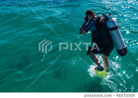 Male scuba diver with equipment jumps in water Male scuba diver with equipment jumps in water 48878509