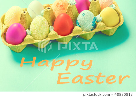 Bright Easter eggs lie in a box on a blue background 48880812