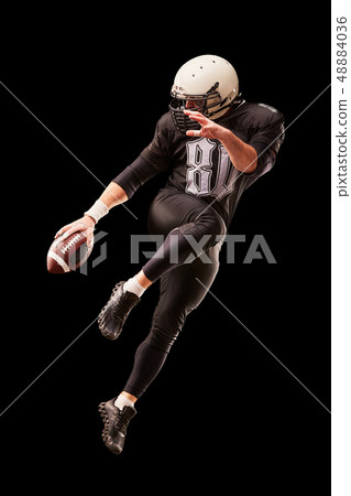 American football player in a jump with a ball on a black background 48884036