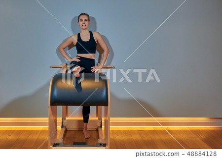 Beautiful girl - a trainer in a sports short top and sports leggings does stretching and stretching Beautiful girl - a trainer in a sports short top and sports leggings does stretching and stretching 48884128