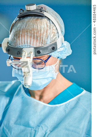 Close up portrait of female surgeon doctor wearing protective mask and hat during the operation Close up portrait of female surgeon doctor wearing protective mask and hat during the operation 48884465