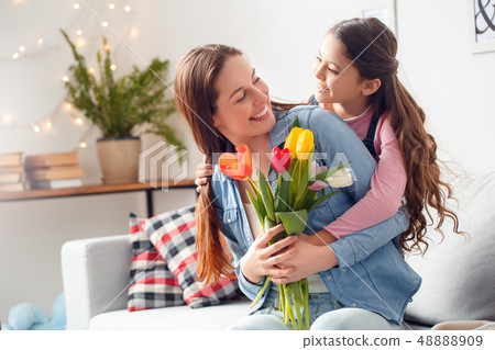 Mother and daughter at home mother's day daughter hugging mother with bouquet of flowers happy Mother and daughter at home mother's day daughter hugging mother with bouquet of flowers happy 48888909