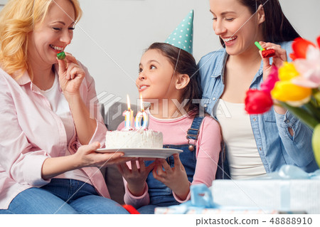Grandmother mother and daughter together at home birthday sitting girl holding cake smiling close-up Grandmother mother and daughter together at home birthday sitting girl holding cake smiling close-up 48888910
