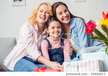 Grandmother mother and daughter together at home celebration sitting hugging smiling cheerful Grandmother mother and daughter together at home celebration sitting hugging smiling cheerful 48888913