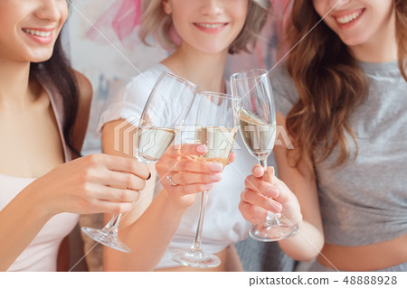 Hen-Party. Young women together at home sitting on sofa drinking champagne cheers smiling cheerful Hen-Party. Young women together at home sitting on sofa drinking champagne cheers smiling cheerful 48888928