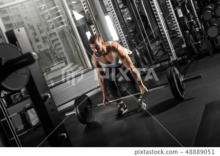 Bodybuilding. Bearded man exercising at gym bending down with barbell concentrated side view Bodybuilding. Bearded man exercising at gym bending down with barbell concentrated side view 48889051