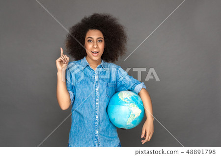 Idea for travel. Mulatto woman standing isolated on grey with terrestrial globe pointing up smiling Idea for travel. Mulatto woman standing isolated on grey with terrestrial globe pointing up smiling 48891798