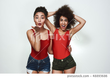 Feeling happy! Cute afro american woman in casual clothing sending an air kiss while while standing Feeling happy! Cute afro american woman in casual clothing sending an air kiss while while standing 48893686