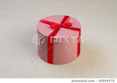 Round pink giftbox with red ribbon Round pink giftbox with red ribbon 48894479