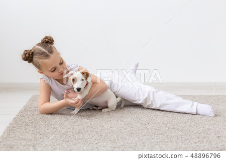 Childhood, pets and dogs concept - Little child girl posing on the floor with puppy 48896796